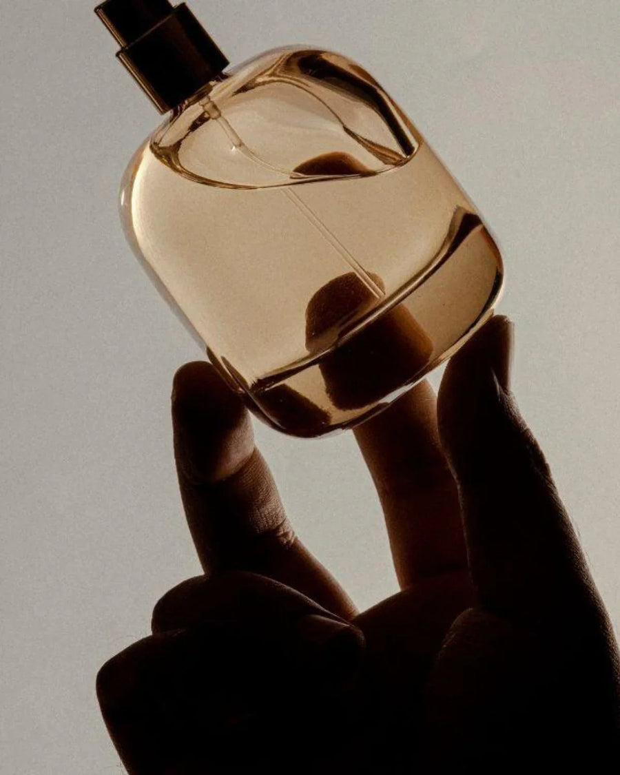 Hand holding a clear glass bottle of chestnut fragrance oil for candle making